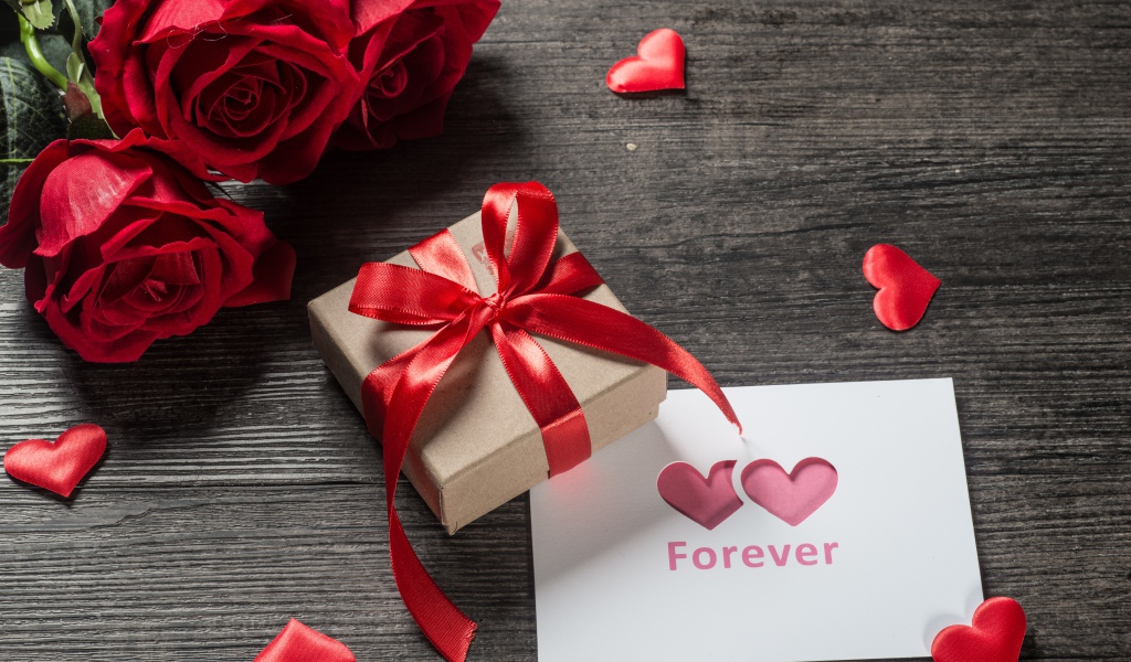 Букет красных роз с подарком и открыткой на столе