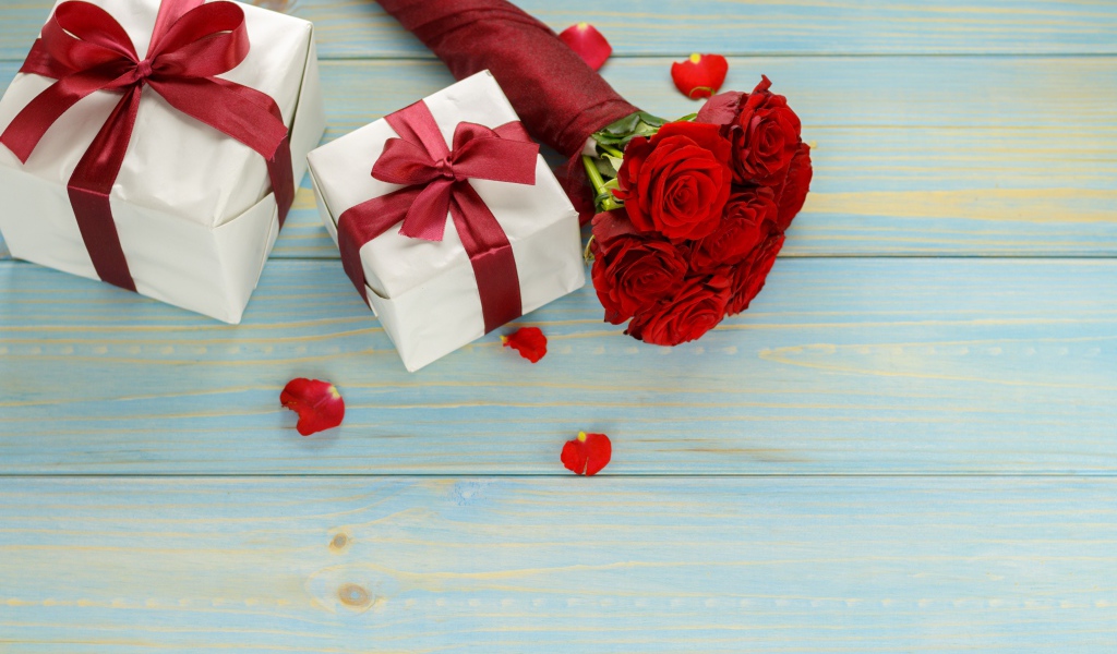 Букет красных роз с подарками на столе