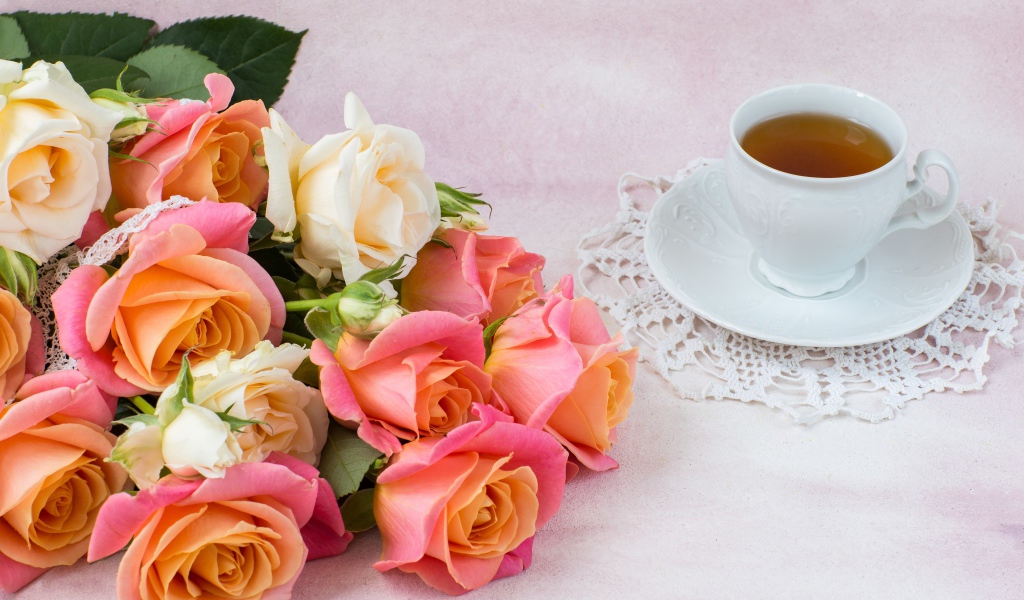 Красивый букет нежных роз на столе с чашкой чая