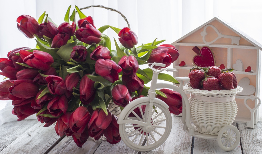Красивый букет красных тюльпанов на столе с клубникой 