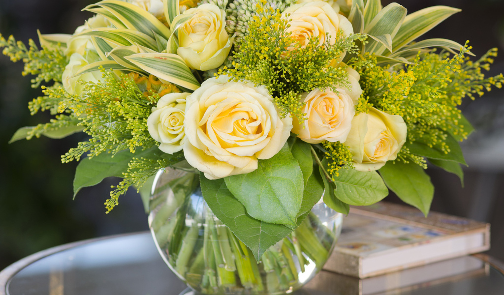 Красивый букет роз с зелеными листьями в в вазе на стеклянном столе