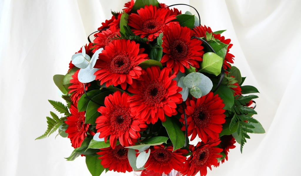 Красивый букет с красными герберами и зелеными листьями 