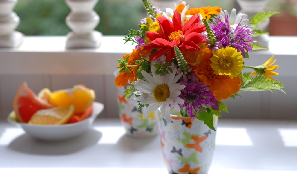 Букет разноцветных  садовых цветов в вазе на столе 