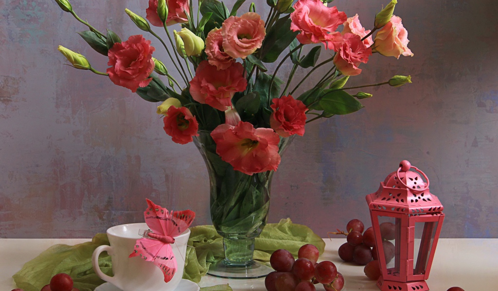 Букет розовых цветов эустомы на столе с виноградом