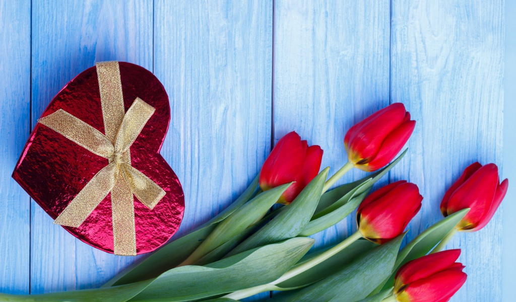 Букет красных тюльпанов на синем фоне с подарком в форме сердца