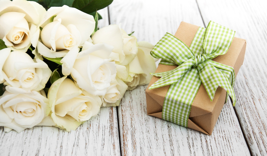 Букет белых роз на столе с подарком
