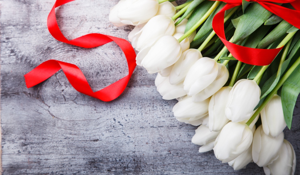 Букет белых тюльпанов с красным бантом на сером столе