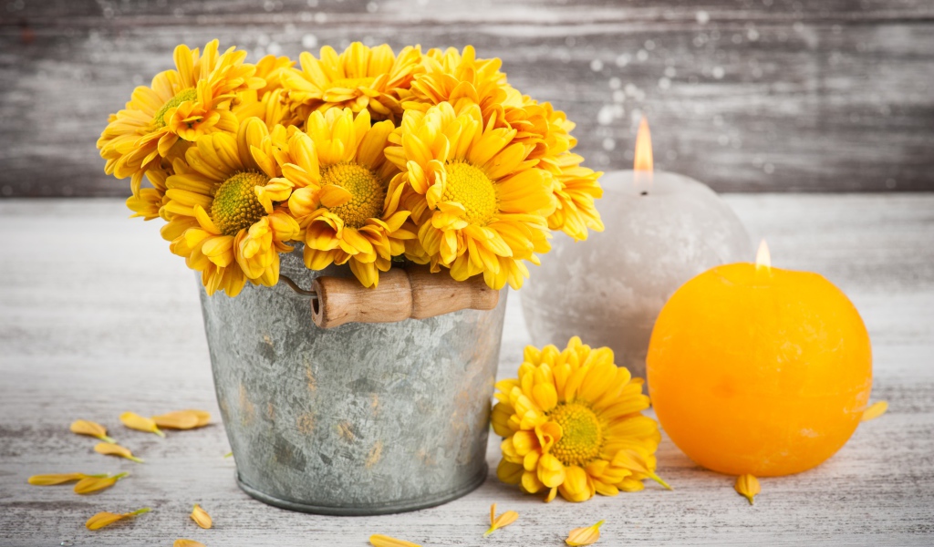 Букет желтых хризантем в ведерке на столе со свечами