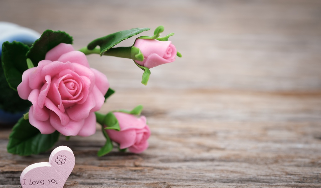 Розовые искусственные розы с сердцем на деревянном фоне