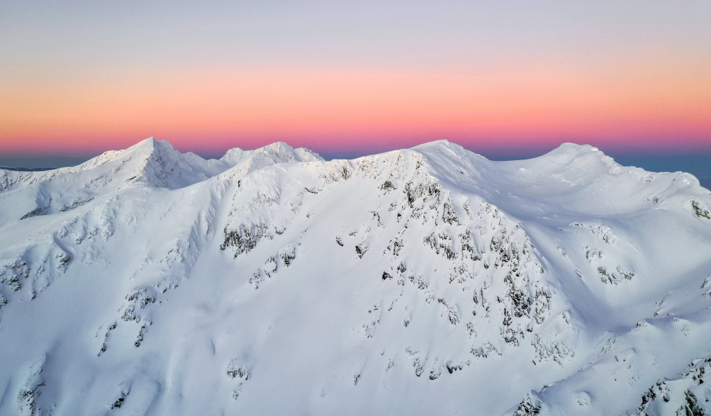 Красивые заснеженные вершины горы на фоне розового неба