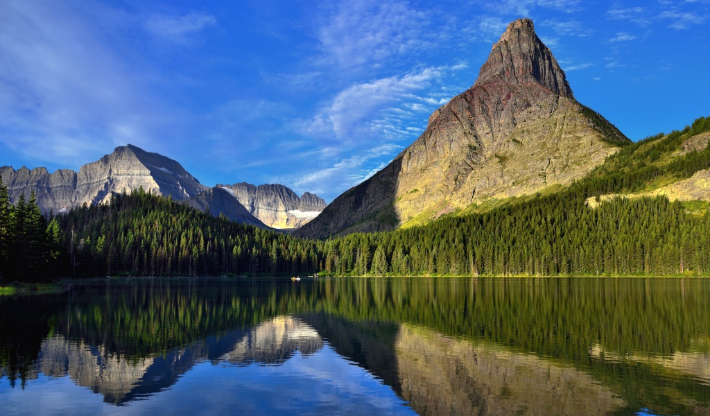 Каменные горы под голубым небом отражаются в воде