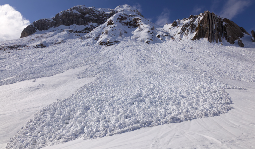 Белая лавина сходит с гор солнечным днем