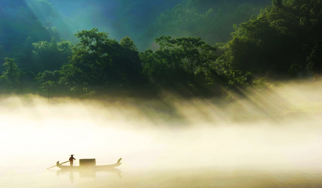 Лодка на туманном озере в лучах солнца 
