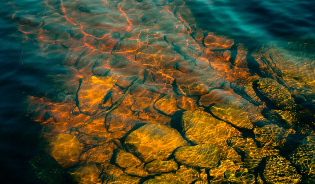 Камни на дне озера с чистой водой в лучах солнца