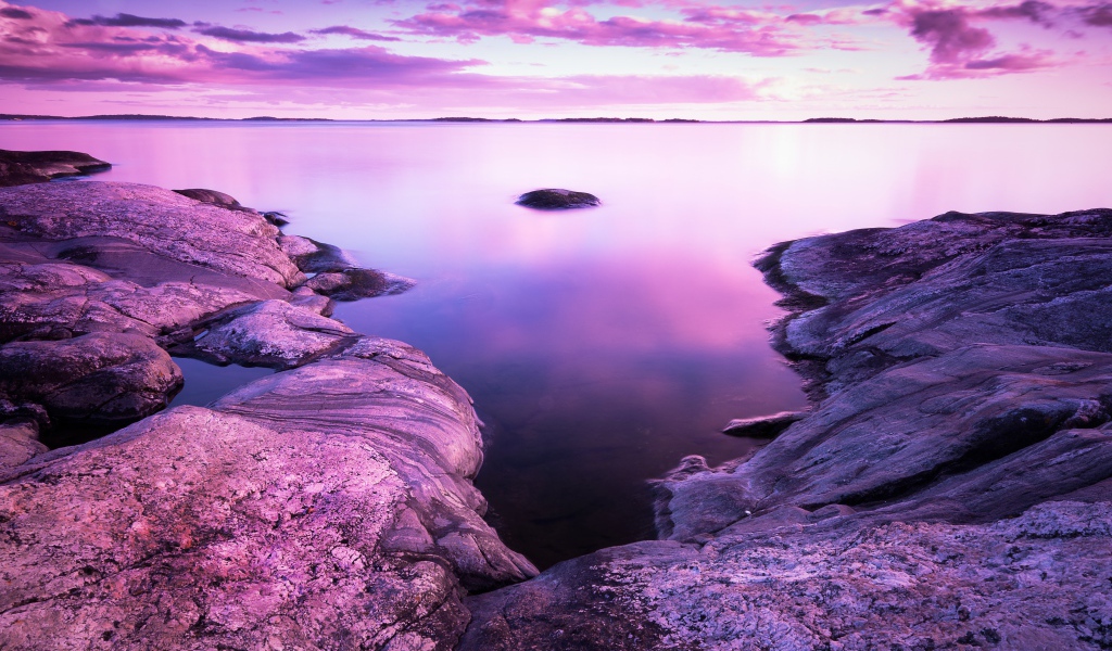 Сиреневый закат в небе над водой и камнями
