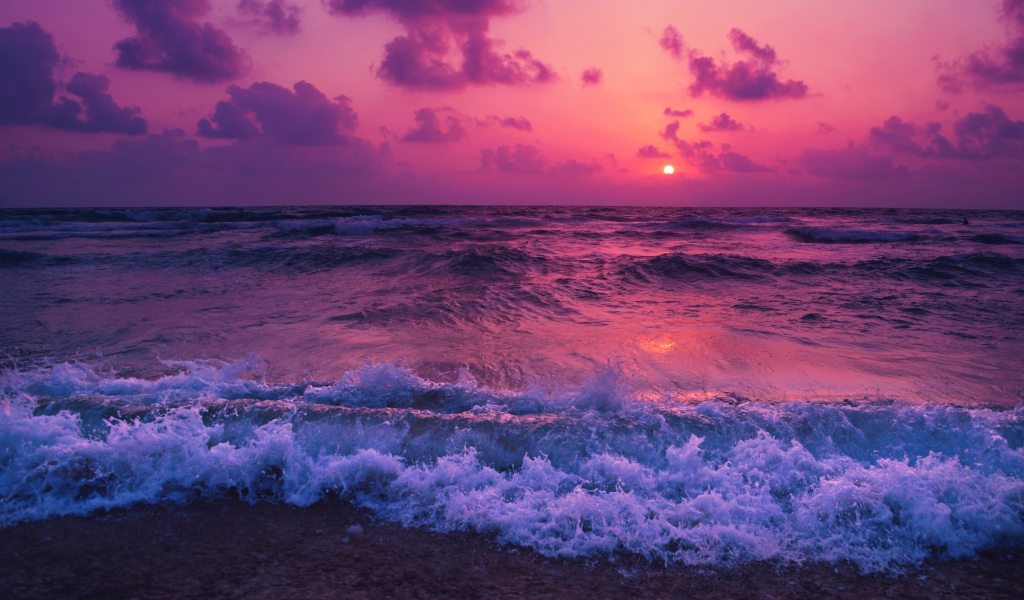 Бушующие волны на берегу на фоне фиолетового закате