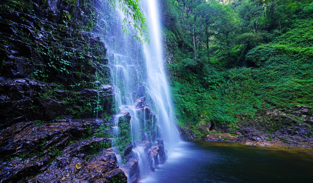 Быстрый водопад стекает по мокрым камням со скалы
