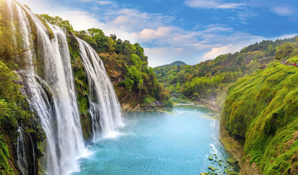 Быстрый водопад стекает с зеленых гор в реку