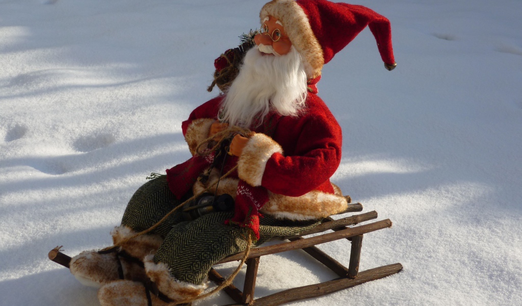 Игрушка деда Мороза на санках стоит на снегу