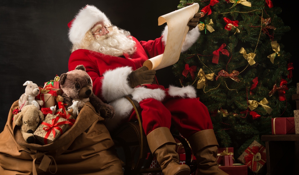 Санта Клаус с мешком подарков читает у елки