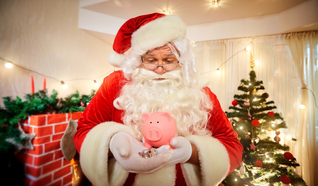 Дед Мороз со свиньей копилкой в руках у новогодней елки