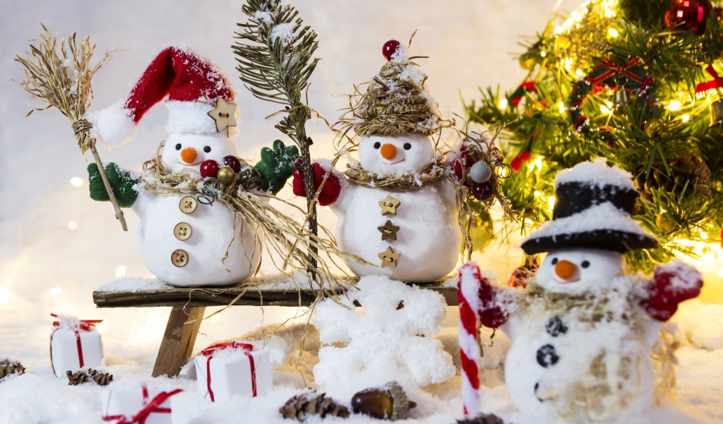 Три снеговика на снегу у искусственной елки на Новый год 