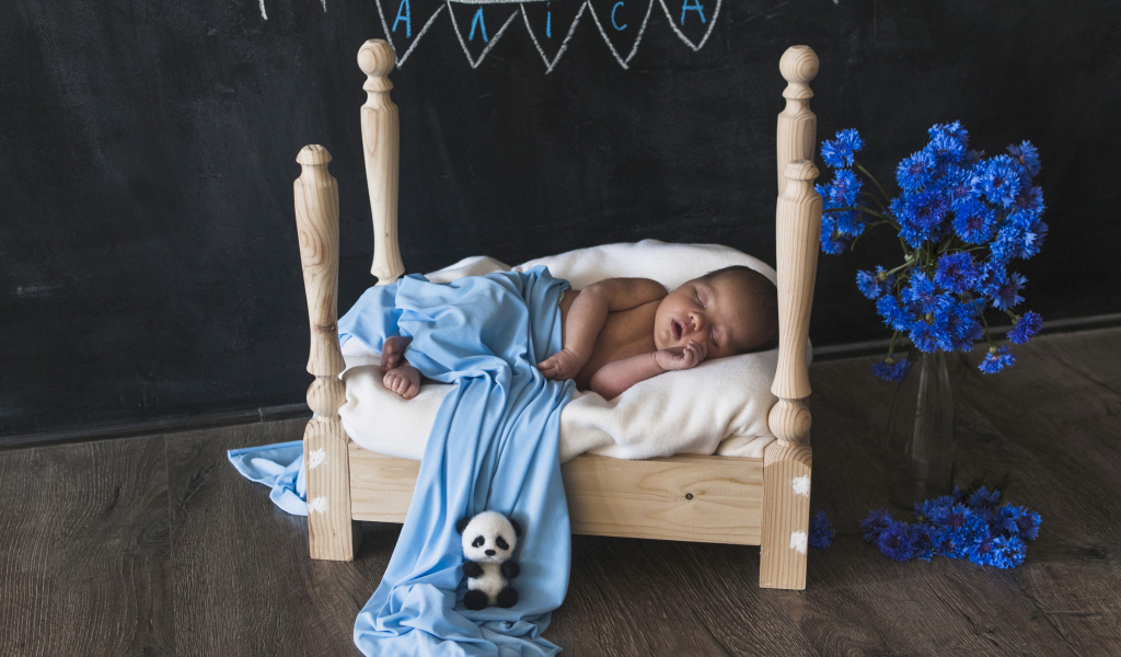 Грудной ребенок спит на деревянной кровати