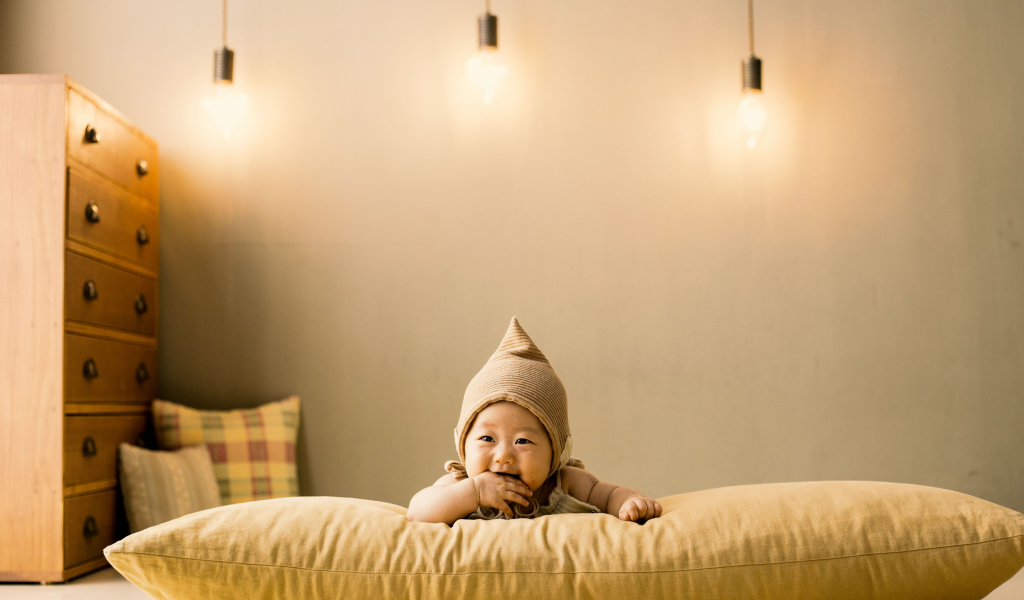 Маленький ребенок лежит на подушке под лампами