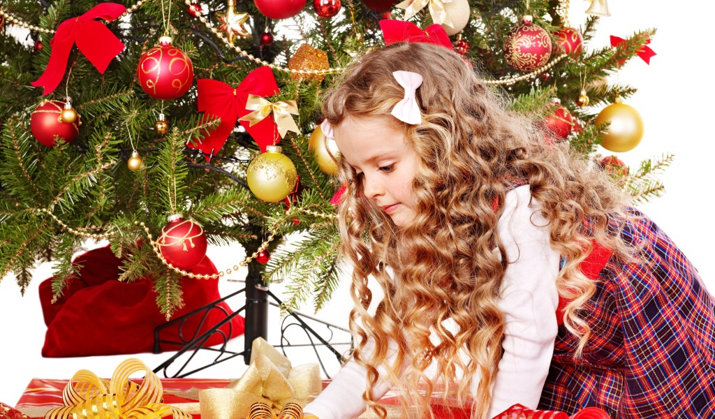 Красивая маленькая девочка смотрит подарки под елкой на новый год 