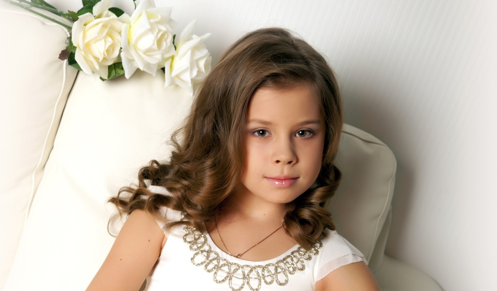 Красивая маленькая девочка сидит в кресле