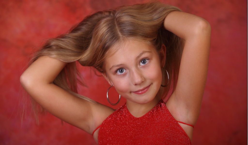 Красивая маленькая девочка с руками в волосах