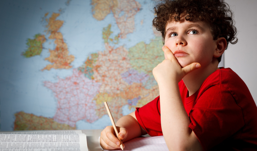 Мальчик ученик делает уроки за столом 