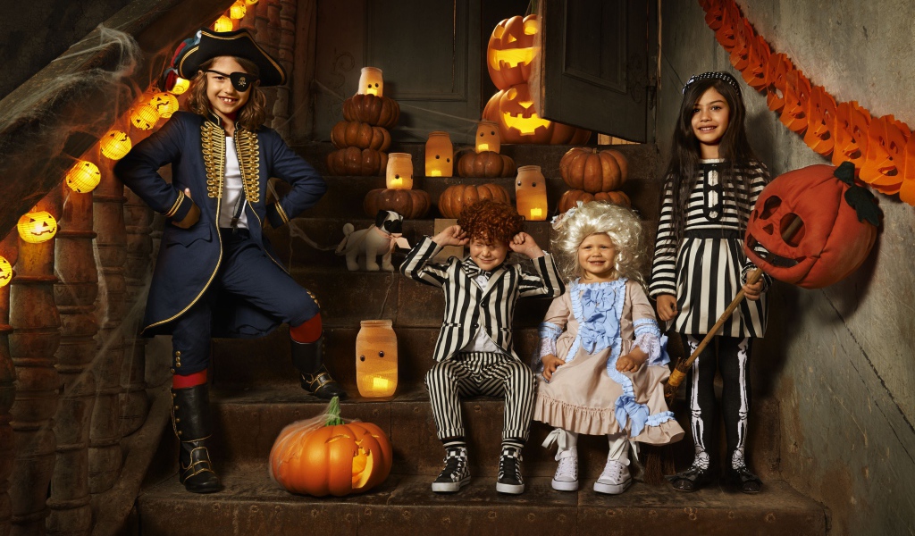 Дети в костюмах на Хэллоуин с тыквами на ступеньках