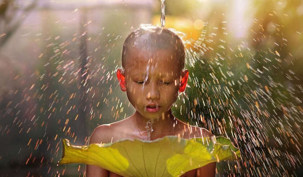 Маленький мальчик азиат умывается водой