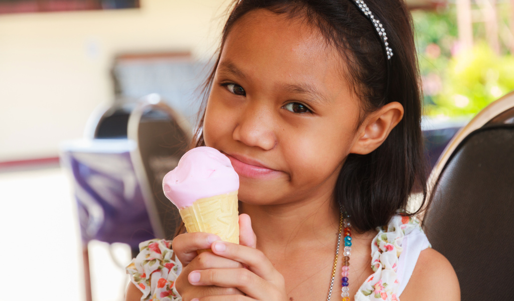 Маленькая девочка азиатка с мороженым в руке