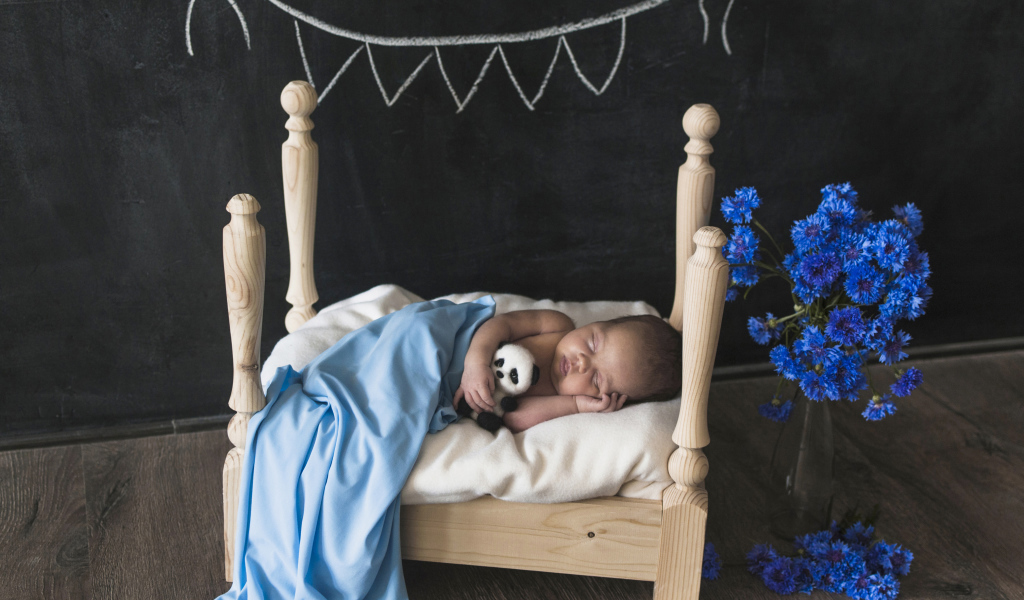 Маленький ребенок спит в деревянной кровати 