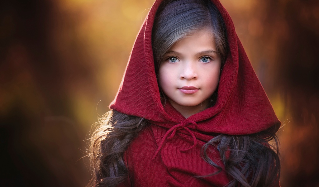 Маленькая красивая голубоглазая девочка с красным капюшоном на голове
