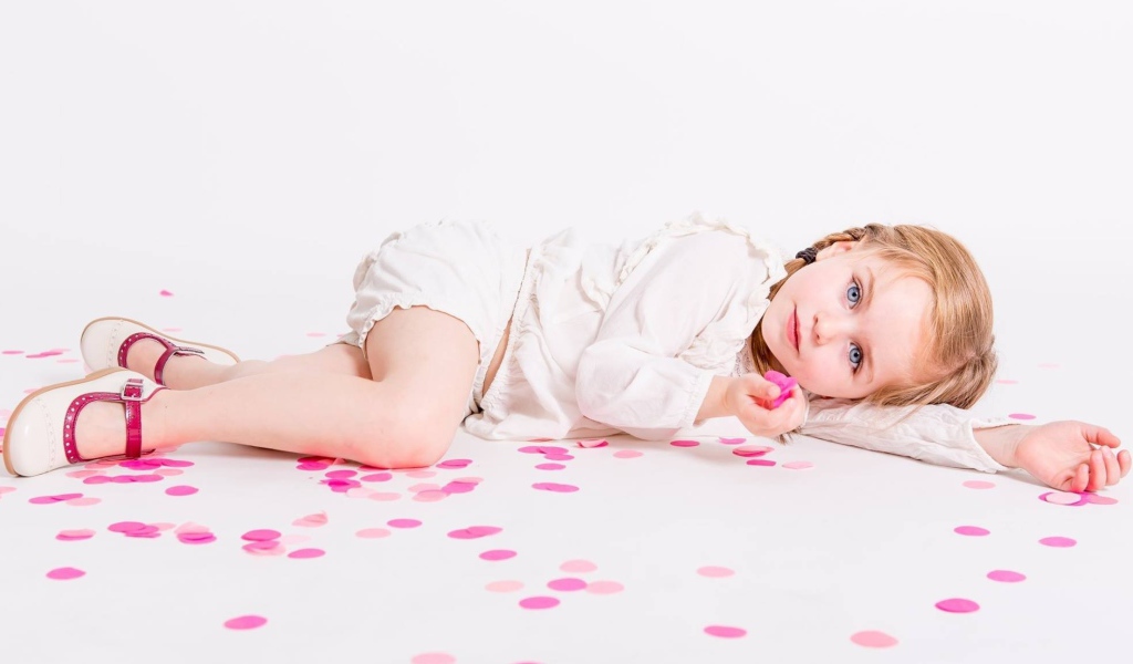 Маленькая голубоглазая девочка лежит на полу