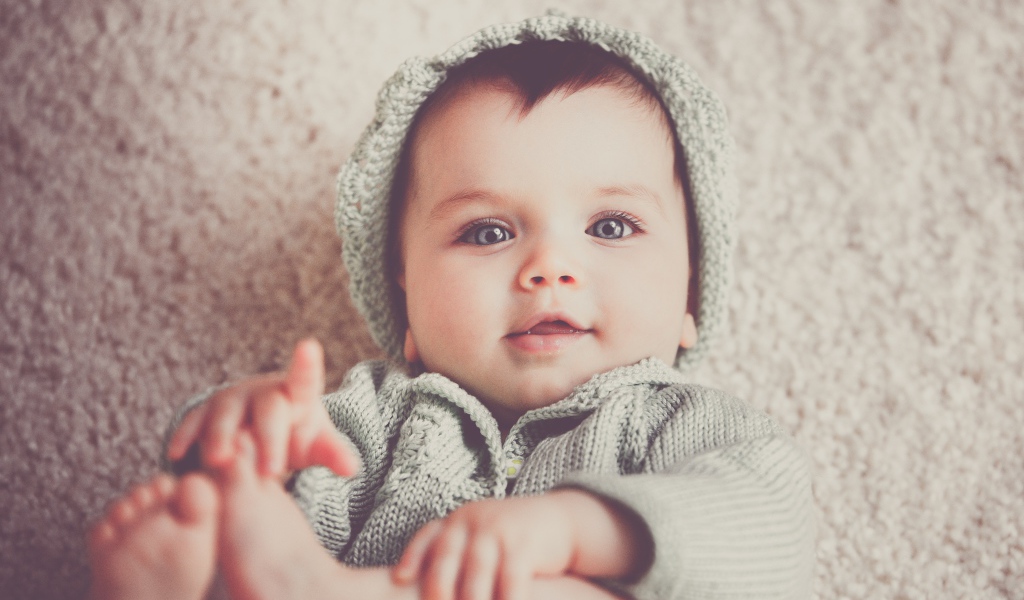 Маленький голубоглазый улыбающийся ребенок в вязаном костюме