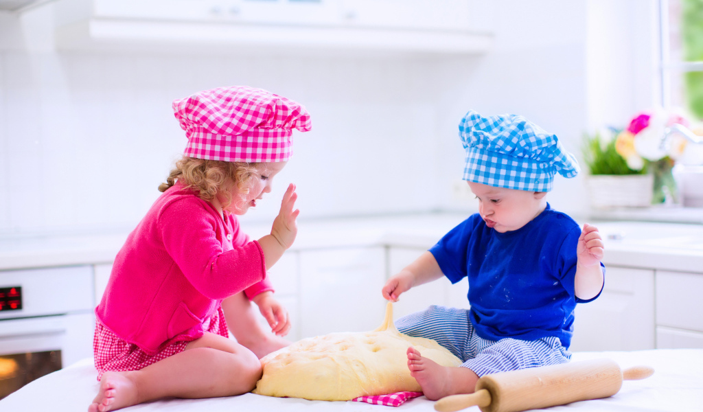 Маленькие мальчик и девочка на кухне с тестом
