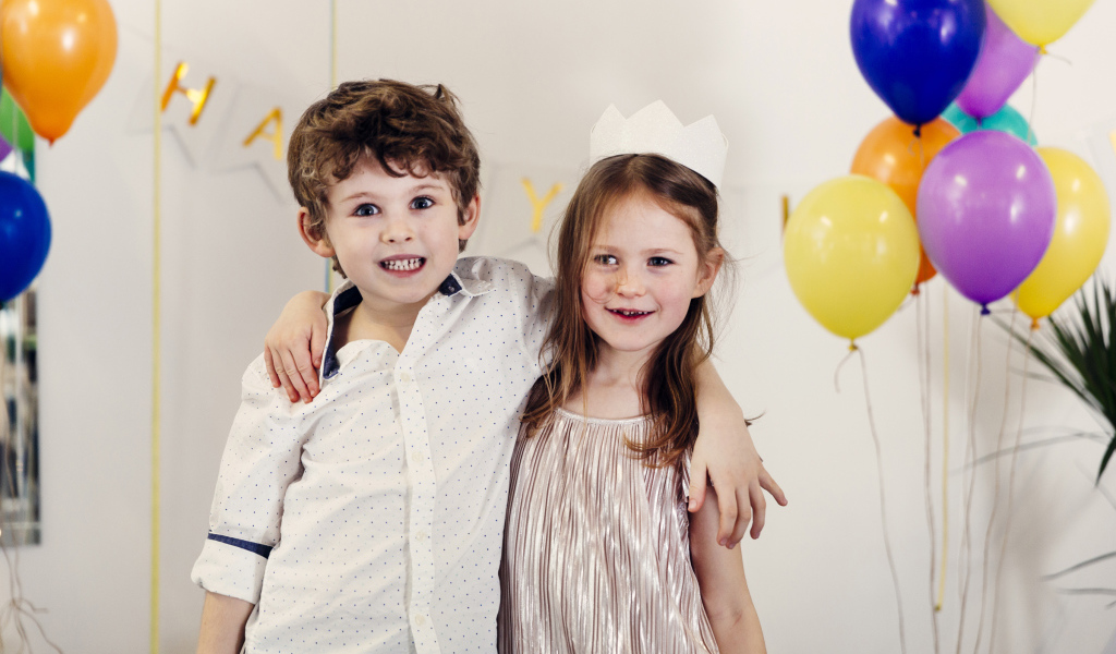 Маленькие мальчик и девочка на празднике с воздушными шарами