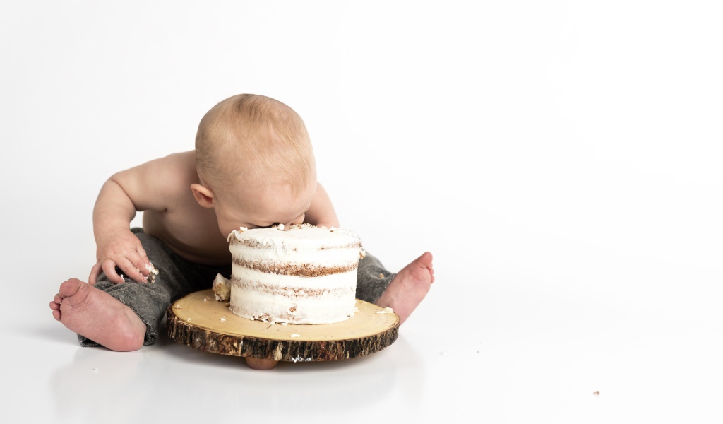 Маленький мальчик ест торт на белом фоне