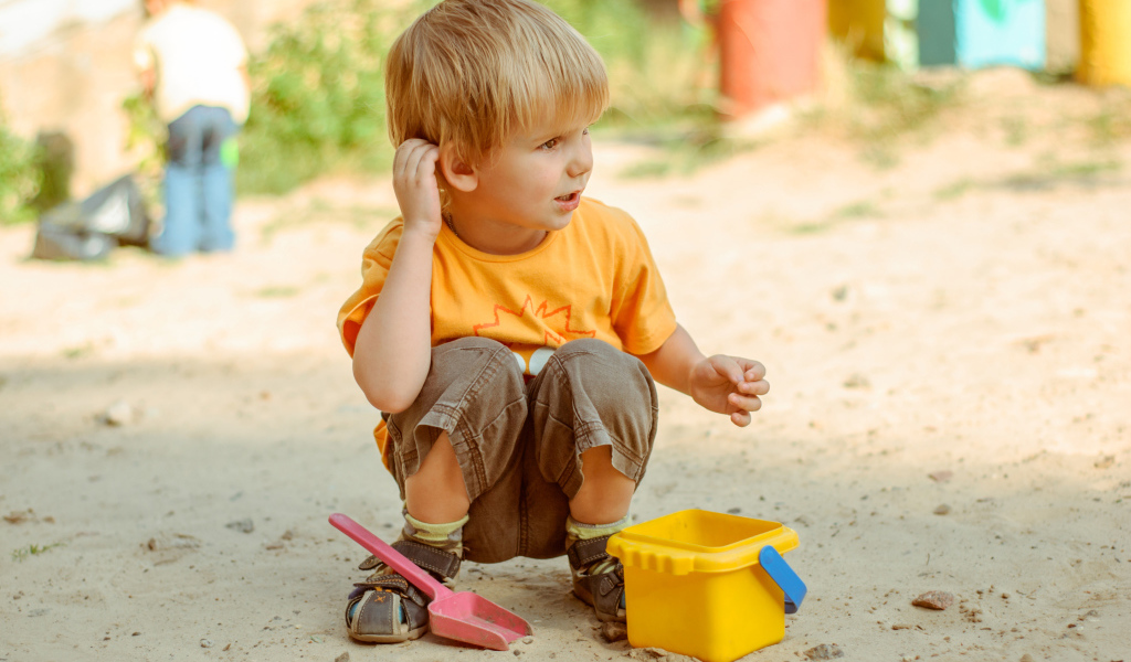Маленький мальчик играет на песке 