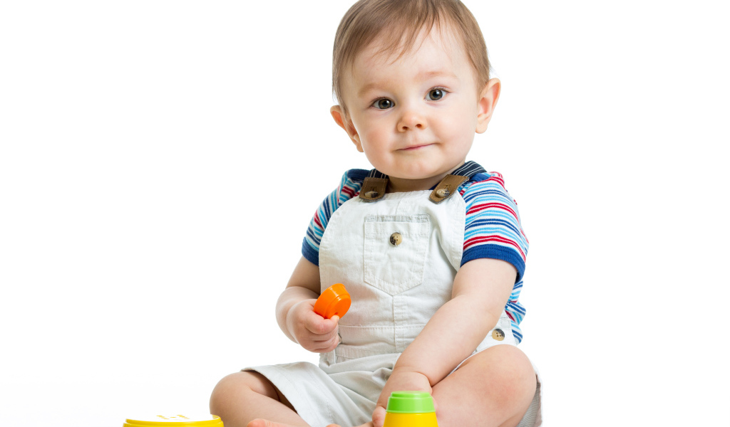 Маленький мальчик играет с пирамидкой на белом фоне