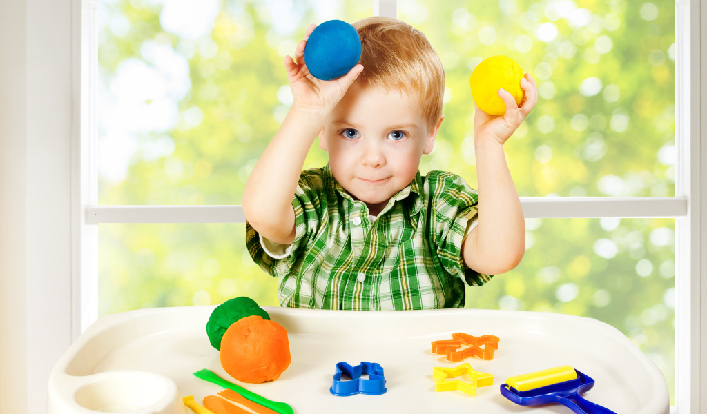 Маленький мальчик играет с игрушками у окна