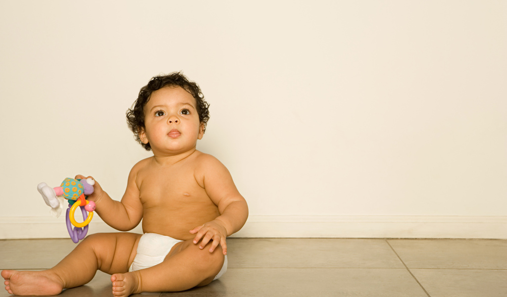 Маленький мальчик сидит на полу с игрушкой