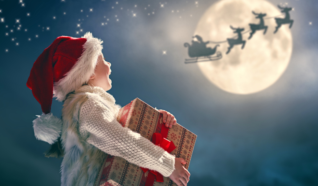 Маленький мальчик с подарком смотрит на улетающего Санта Клауса