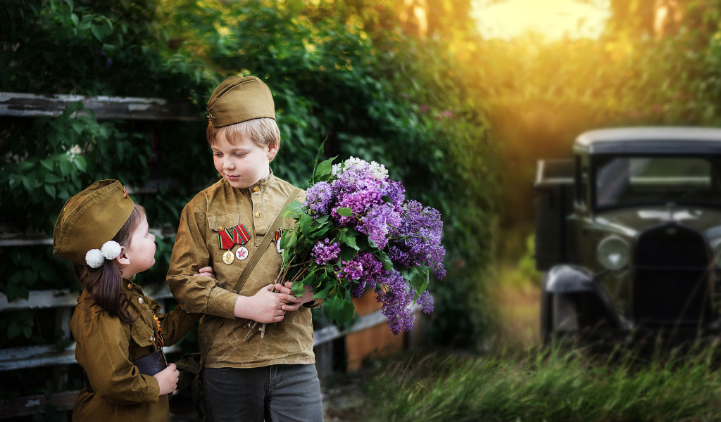 Маленький мальчик с девочкой в военной форме с букетом сирени на 9 мая 