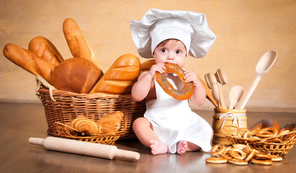 Маленький мальчик с хлебобулочными изделиями на столе 