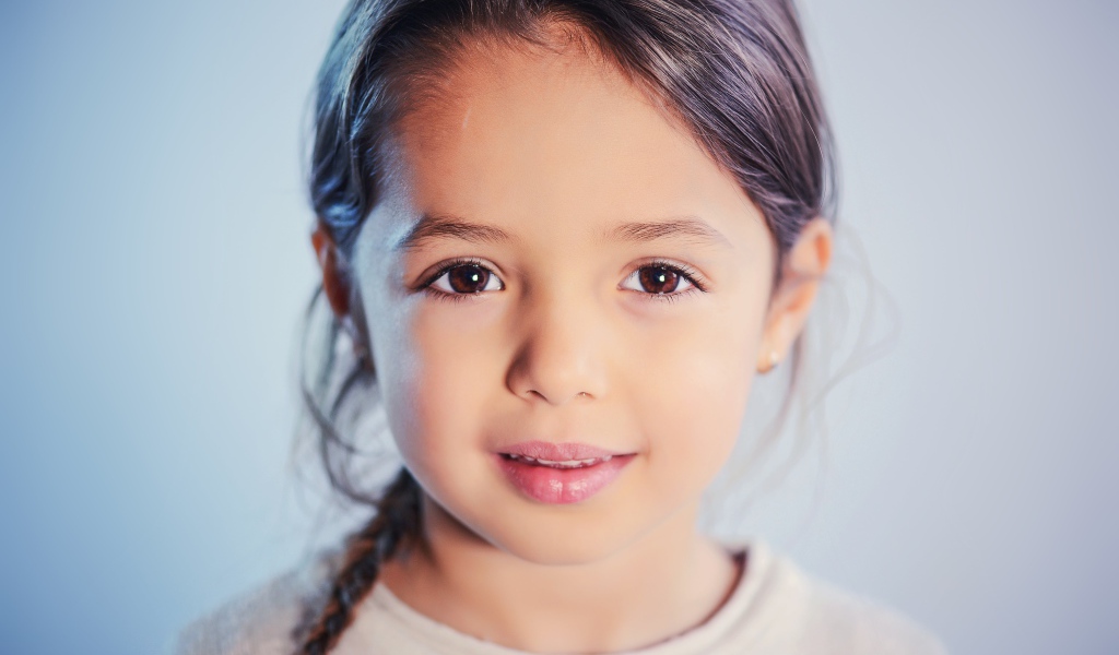 Маленькая кареглазая девочка на сером фоне